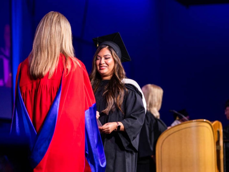 Graduate wearing cap accepts credential on stage
