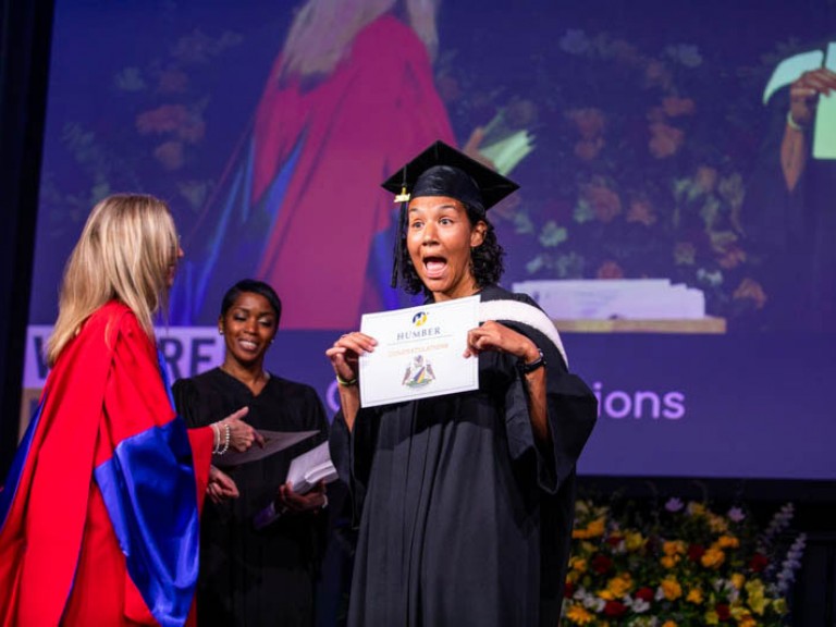 Graduate wearing cap makes excited face on stage