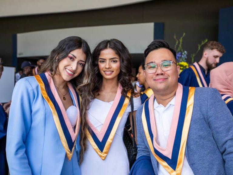 Three graduates pose for photo