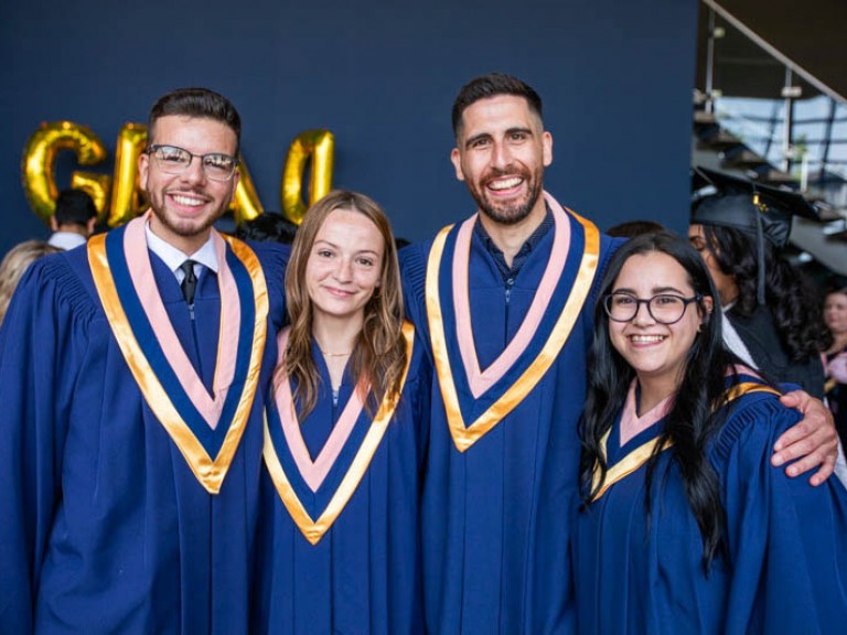 Four graduates smile for camera