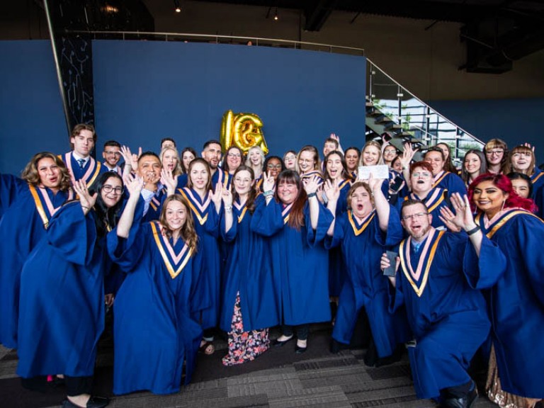 Group of graduates raise hands in celebration