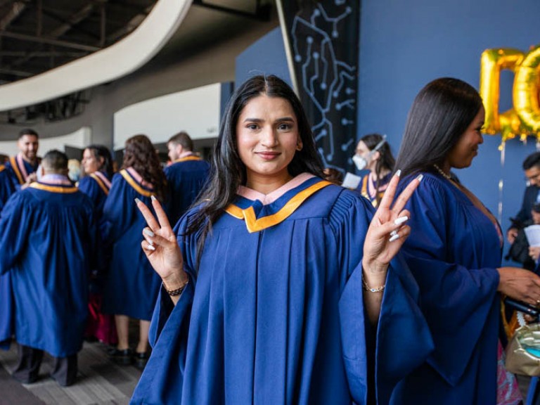 Graduate makes peace signs with her hands