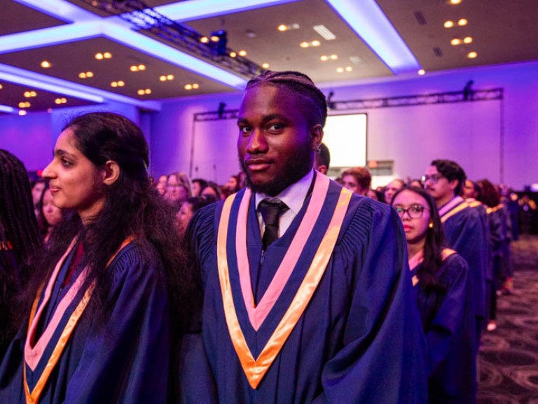 Graduate in audience looks at camera