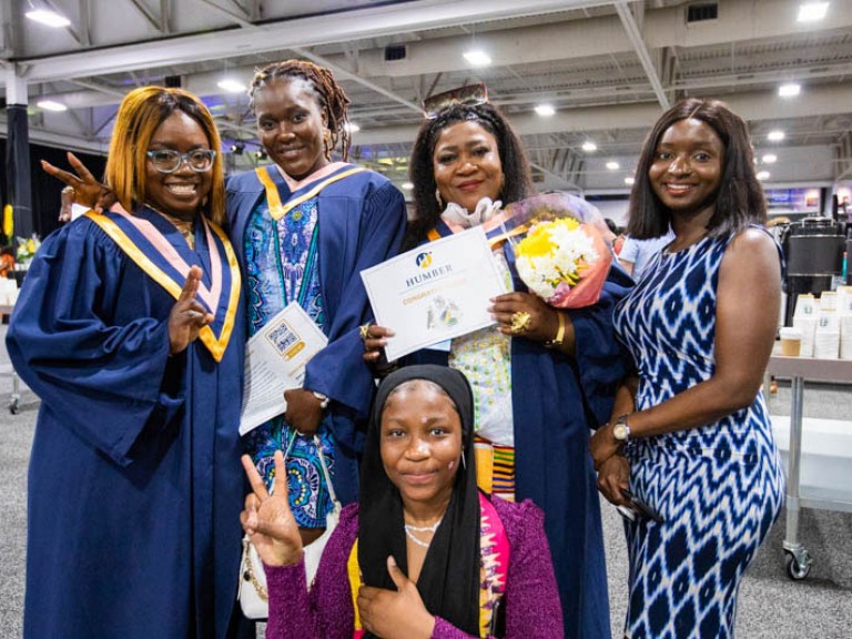 Three graduates pose with two guests