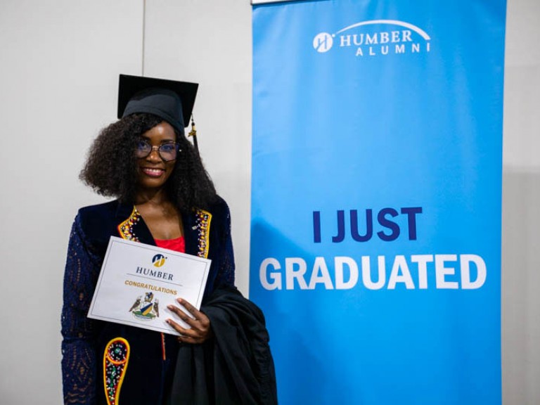 Graduate stands beside banner that reads I Just Graduated