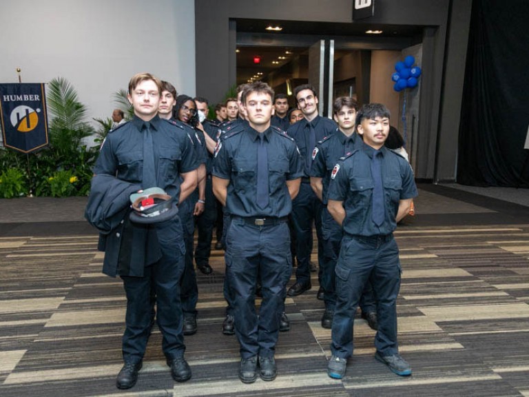 Graduates from a police program standing in uniform in rows