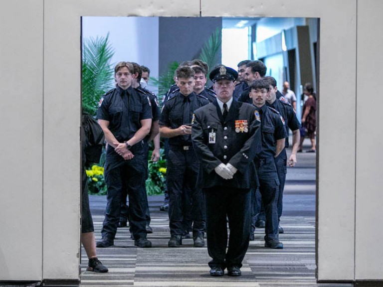 Police graduates in uniform standing in rows behind their leader