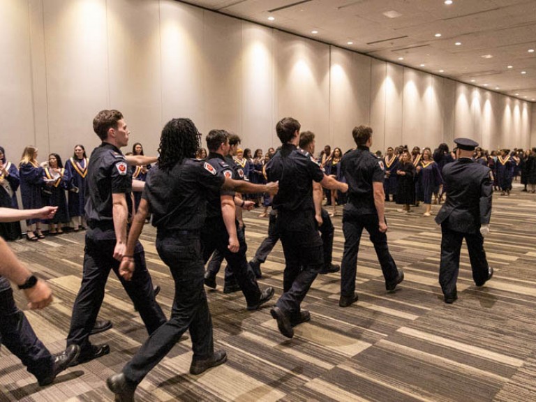 Police graduates walking behind their leader in three rows