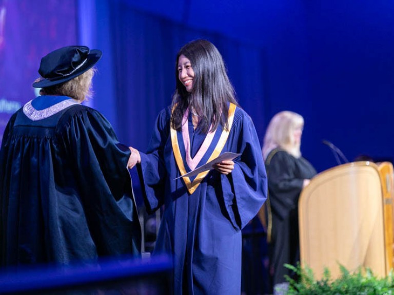 Graduate shakes Humber president's hand after receiving certificate