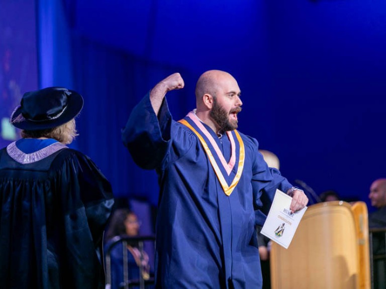 Graduate holds their fist in the air