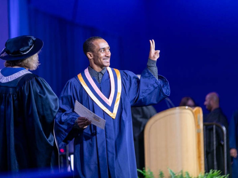 Graduate holds up peace sign