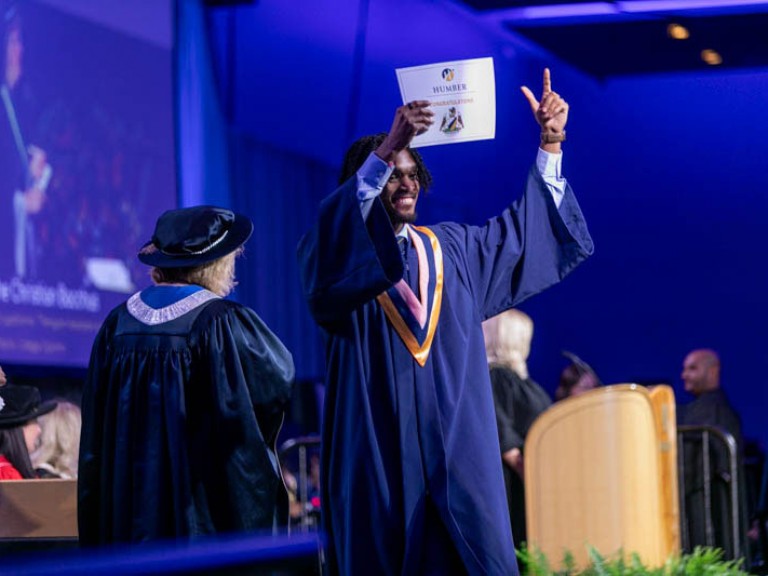 Graduate holds up their certificate