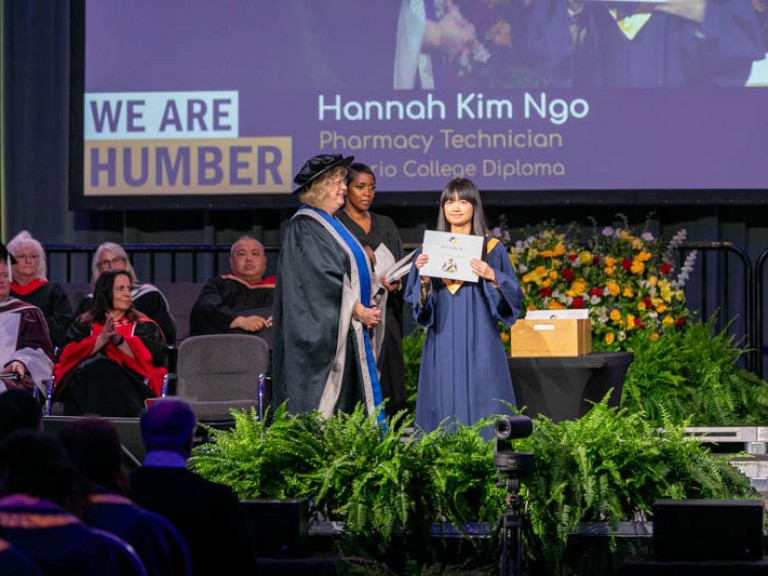 Pharmacy Technicialn graduate Hannah Kim Ngo on stage holding certificate