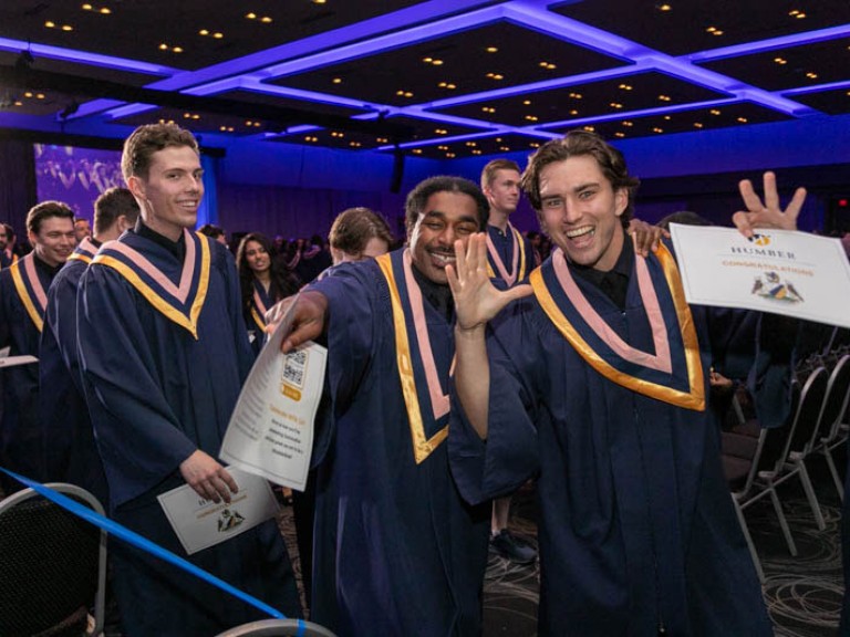 Graduates make excited poses for camera as they leave ceremony hall