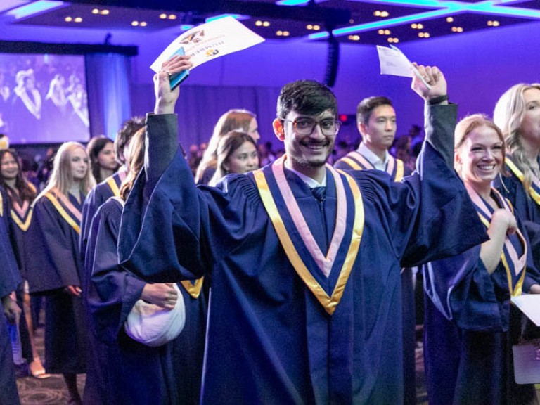 Graduate  raises arms as he leaves the ceremony hall