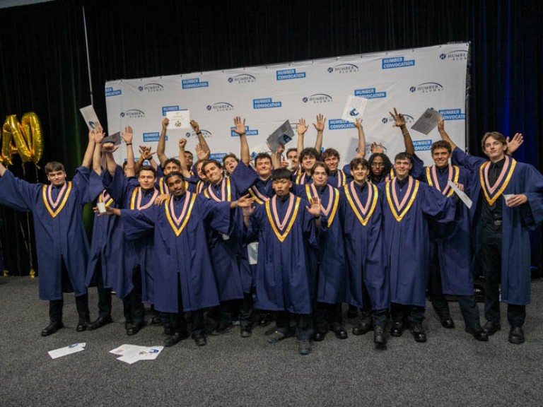 Graduates raise arms in celebration for photo