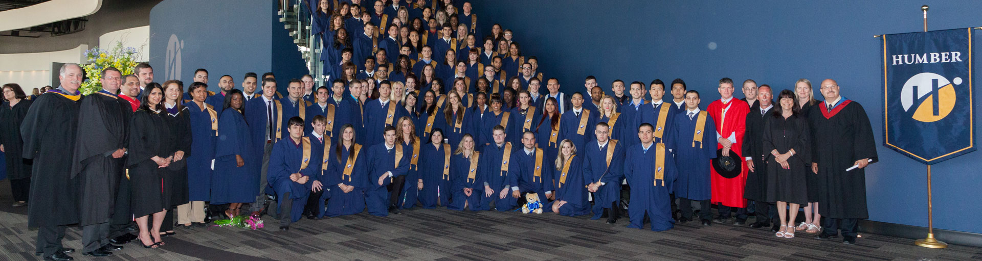 a large group of graduates in their regalia posing at a stairwell