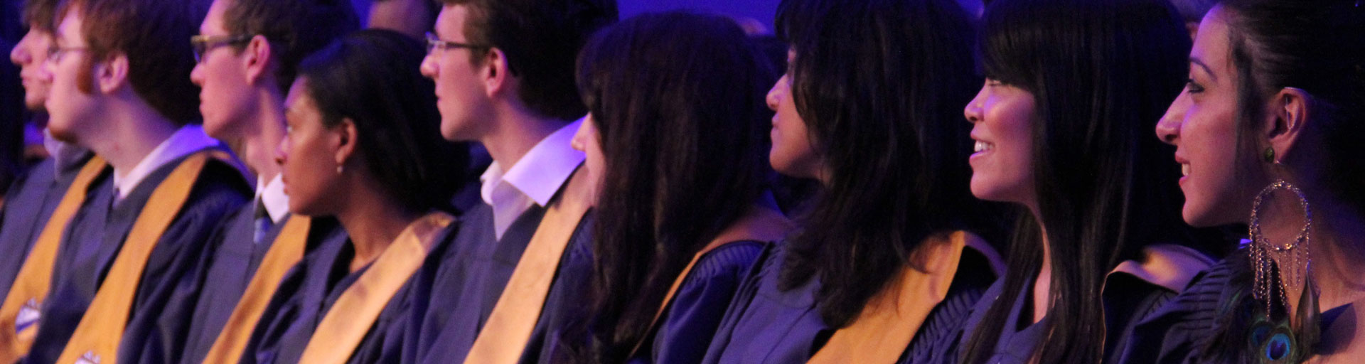 students in regalia sitting in the crowd at the convocation ceremony