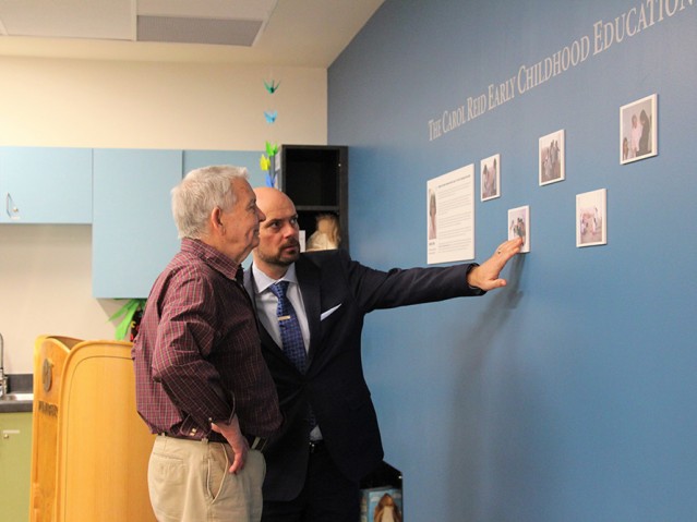 A man describing the other person about the pictures on the wall