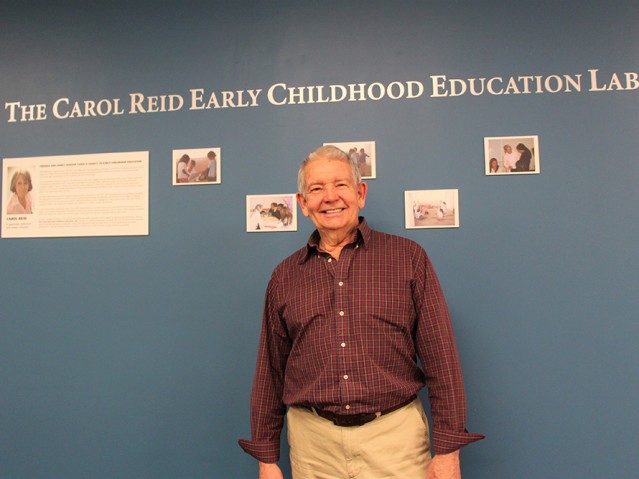 Man getting pictured in front of CAROL REID EARLY CHILDHOOD EDUCATION LAB wall