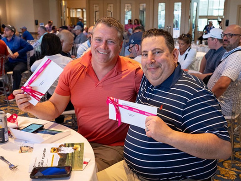 2 people at the golf classic holding prizes smiling