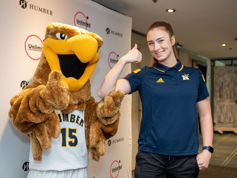Person holding thumbs up next to Humber mascot
