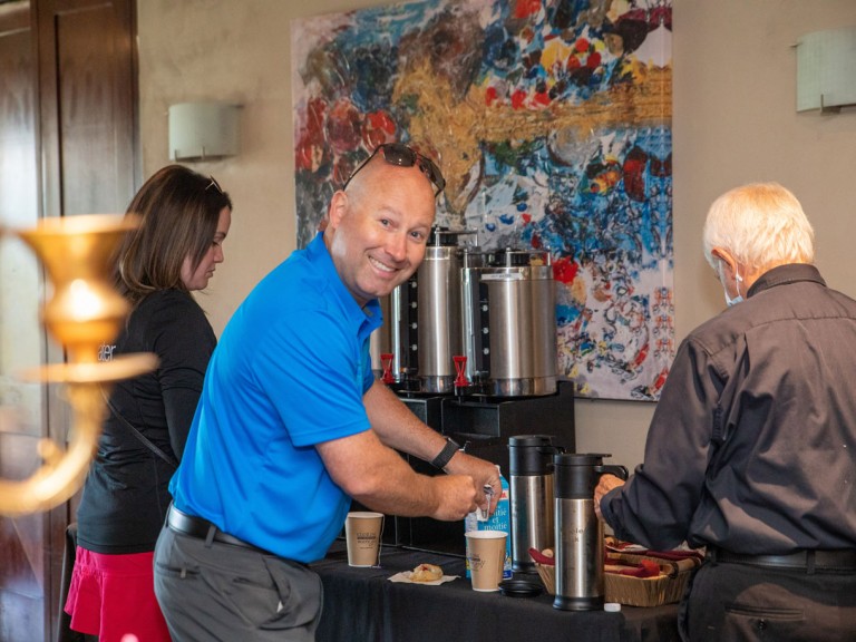 Person making their coffee smiling at camera
