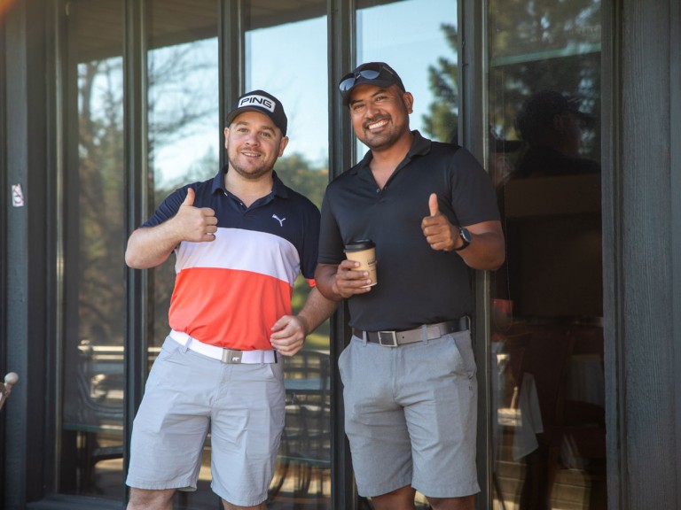 Two people outside building holding thumbs up