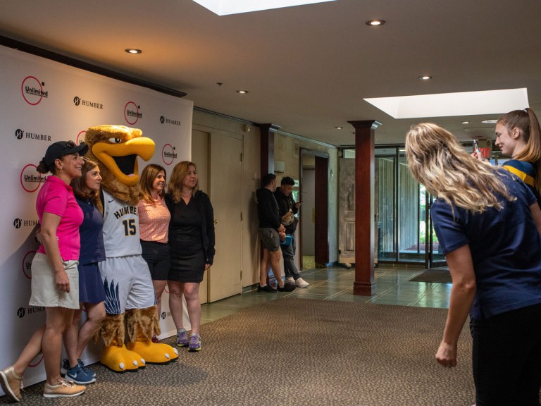 Four people take photo with Humber mascot