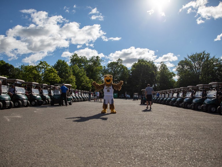 Humber mascot on pavement between rows of golf carts