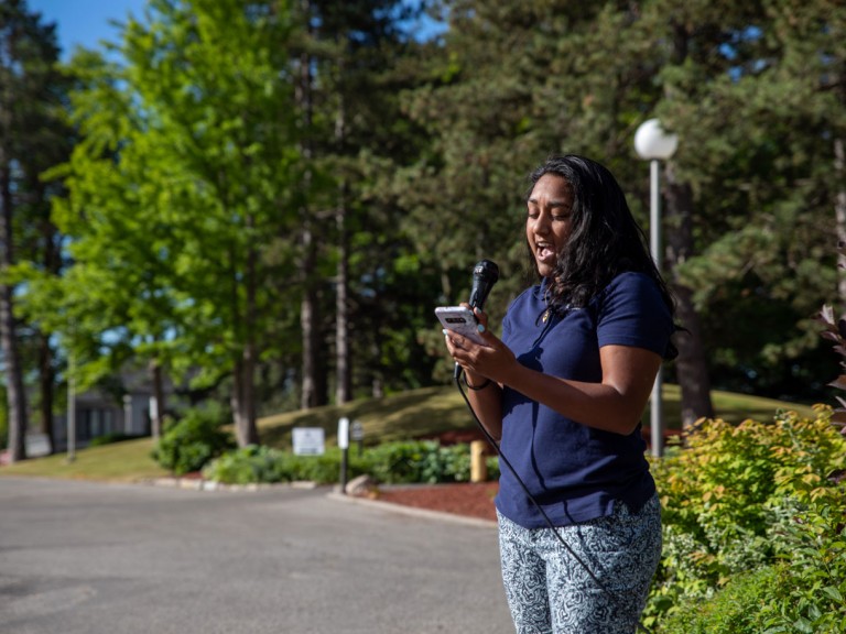 Person with microphone reading from their cell phone