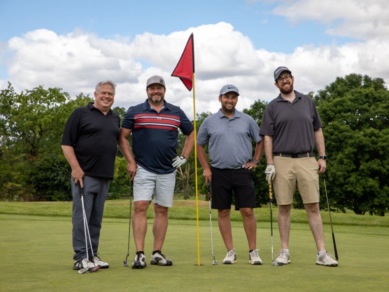 Four people smiling holding their clubs