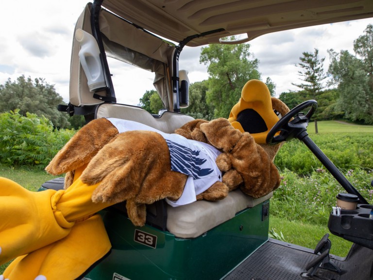 Humber mascot lounging across golf cart seats