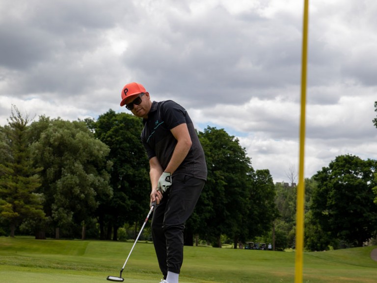 Person shoots golf ball towards hole