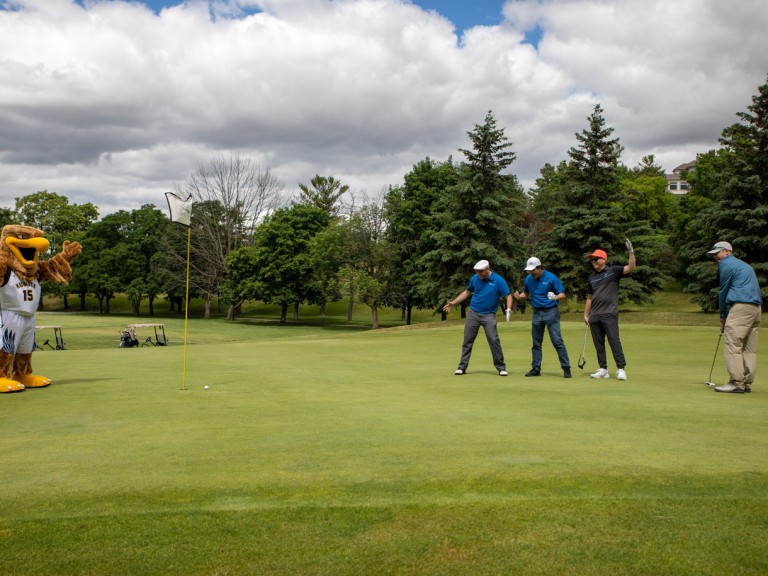 Humber mascot near hole cheering on golfers