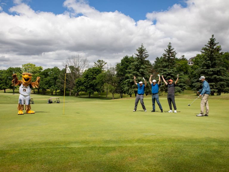 Humber mascot and golfers with arms raised in celebration