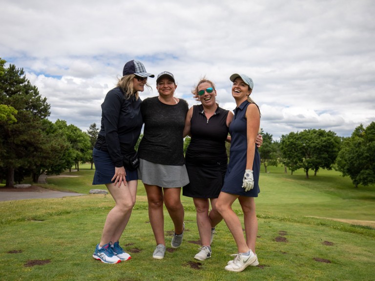 Four golfers pose together on course