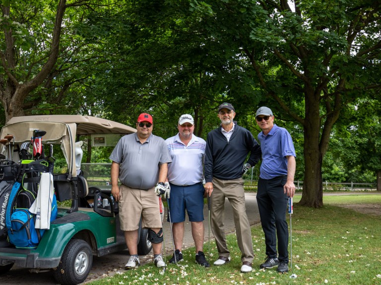 Four people post beside golf cart