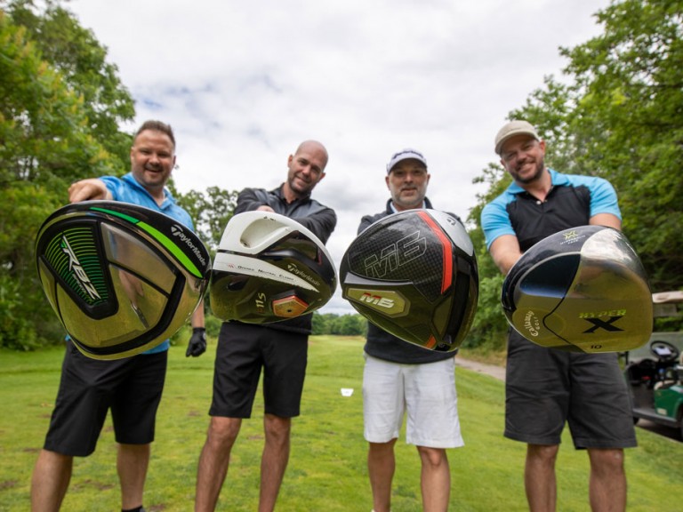 Four people hold their golf clubs towards camera