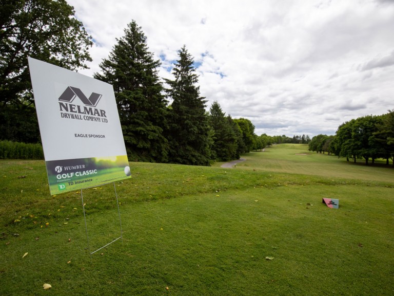 Banner on golf course that reads: Nelmar Drywall Company Eagle Sponsor