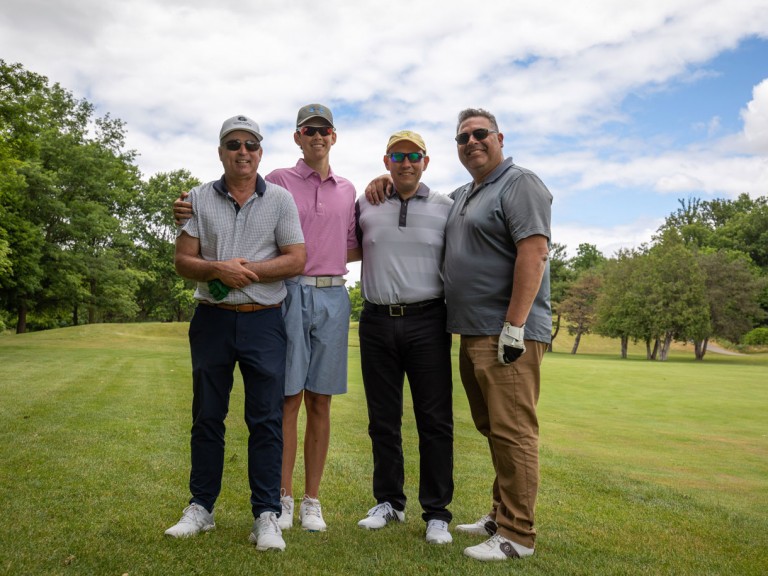 Four people pose on golf course