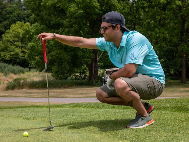 Person kneeling next to golf ball