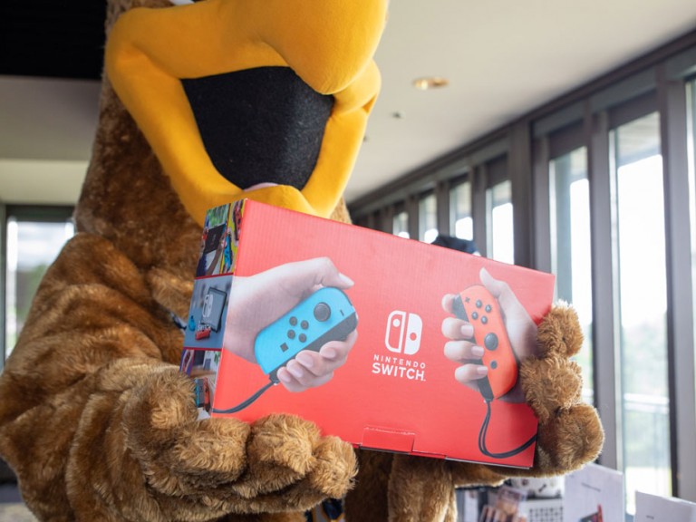 Humber mascot holding a Nintendo switch box