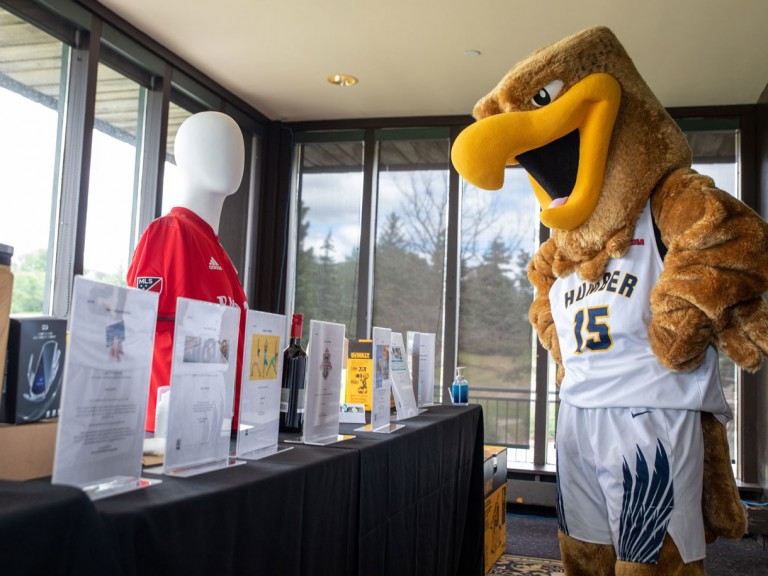 Humber mascot looking at table of prizes