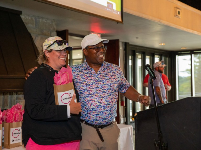 Two people smiling with gift bags behind podium