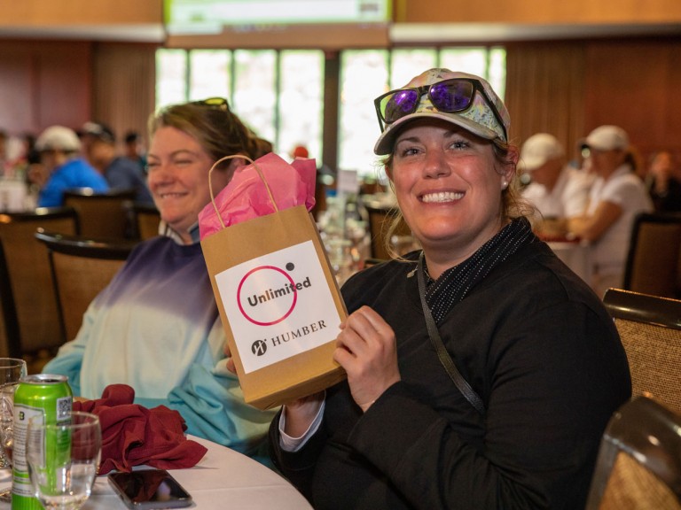 Person smiling with gift bag at table