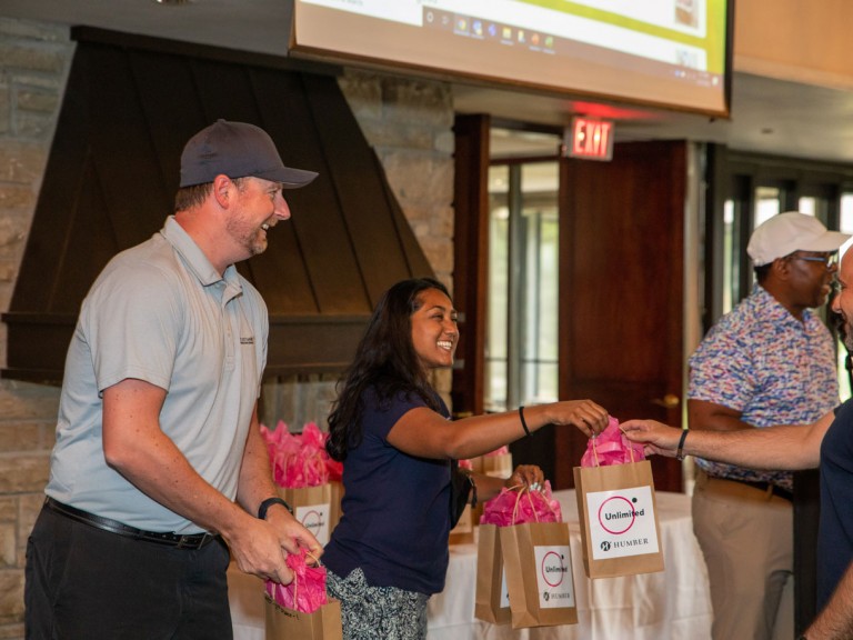 Two people smiling handing out gift bags