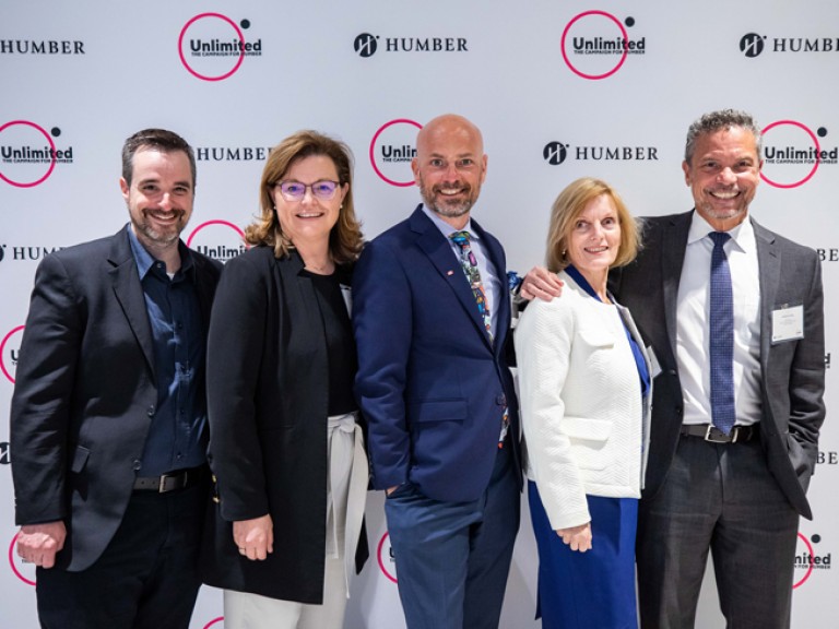 Five people smiling in front of Humber Unlimited backdrop wall