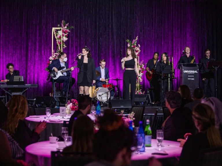 Band performing on stage with audience members watching