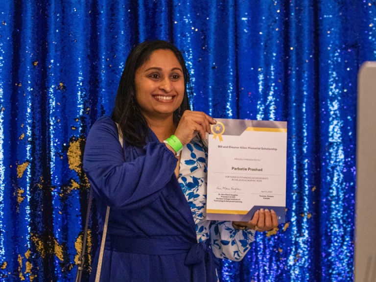 Person holding their award poses for photo